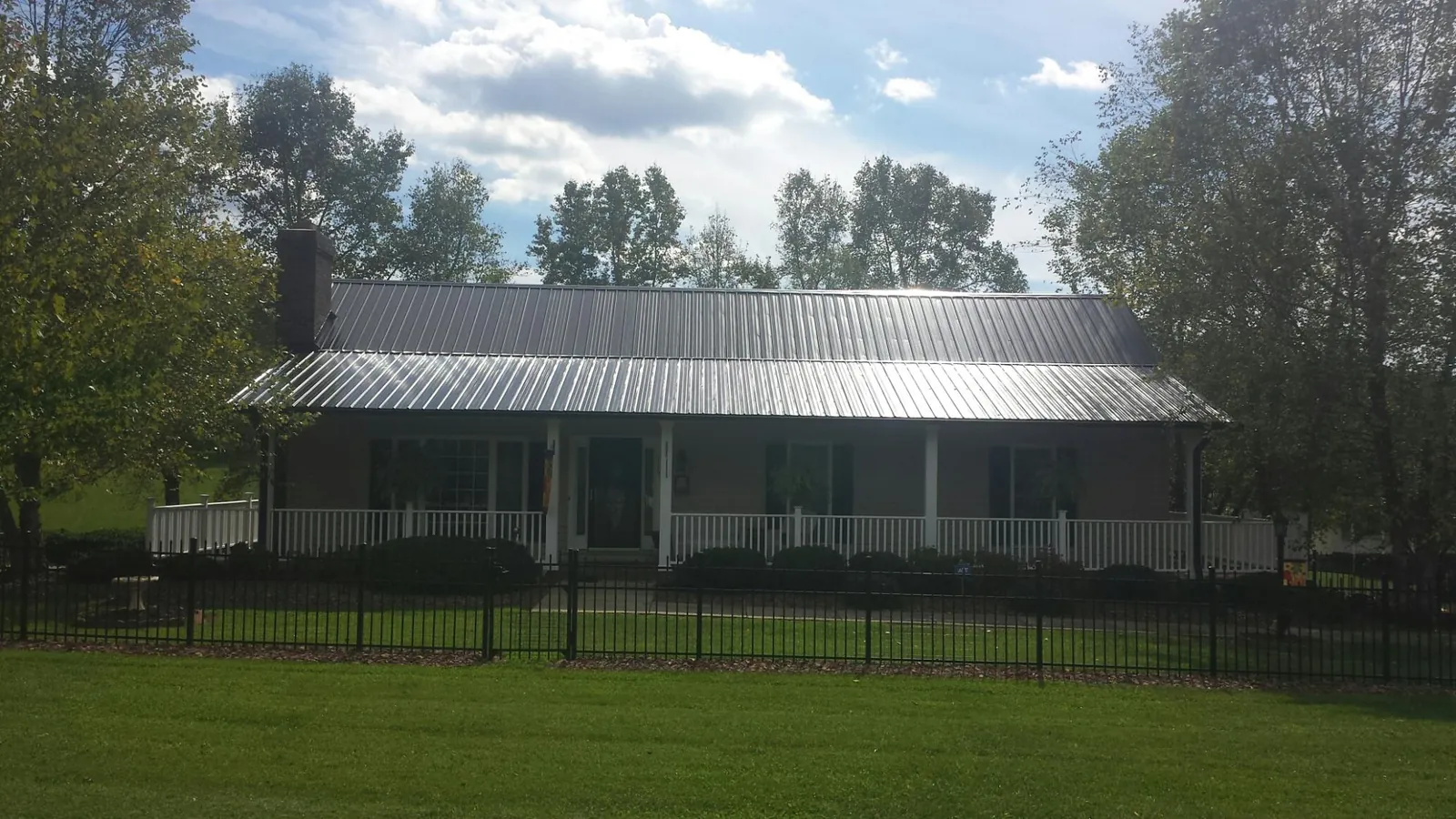 Gray metal roof on a brick ranch with a full width front porch in Cherry Valley